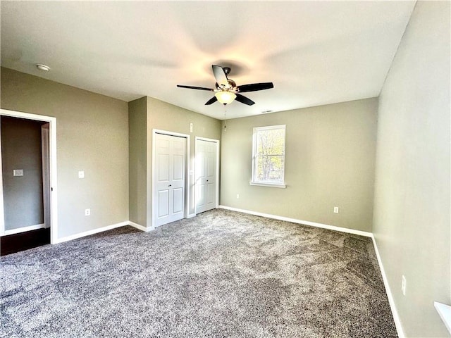 unfurnished bedroom with ceiling fan, carpet flooring, and two closets