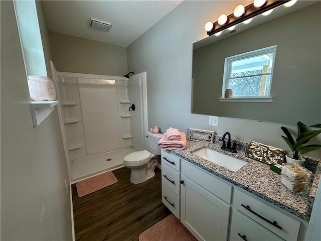 bathroom featuring hardwood / wood-style flooring, a shower, vanity, and toilet