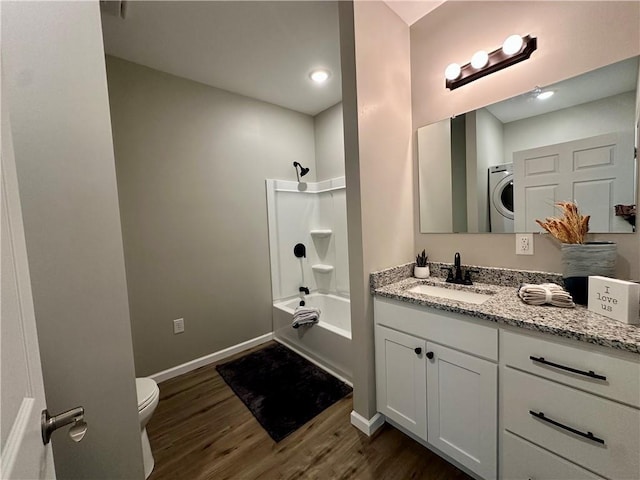 full bathroom with hardwood / wood-style floors, washer / dryer, vanity,  shower combination, and toilet