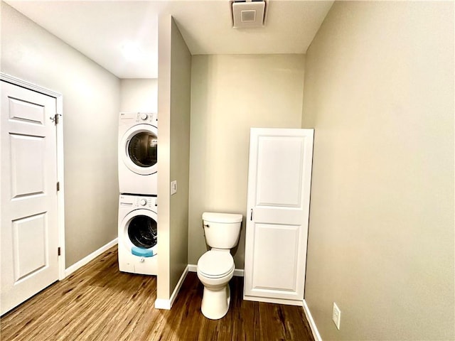 laundry room with hardwood / wood-style flooring and stacked washer / dryer