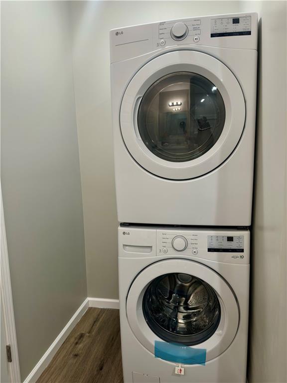 clothes washing area featuring stacked washer and dryer and dark hardwood / wood-style floors