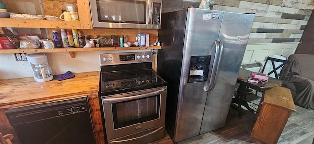 kitchen with wooden walls, hardwood / wood-style floors, and stainless steel appliances