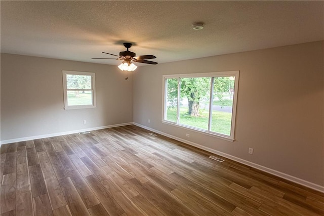 spare room with dark wood-style floors, baseboards, visible vents, and a textured ceiling