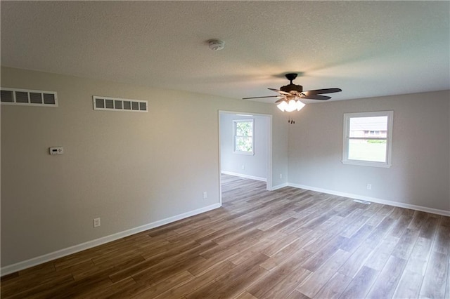 spare room with a healthy amount of sunlight, visible vents, and wood finished floors