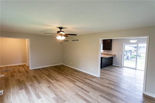 unfurnished room featuring a ceiling fan, visible vents, light wood-style flooring, and baseboards