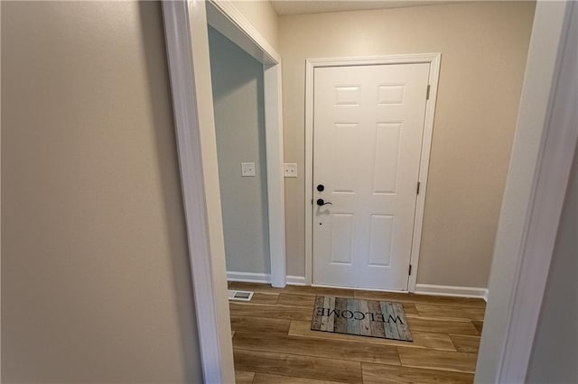 doorway to outside with wood finished floors and baseboards