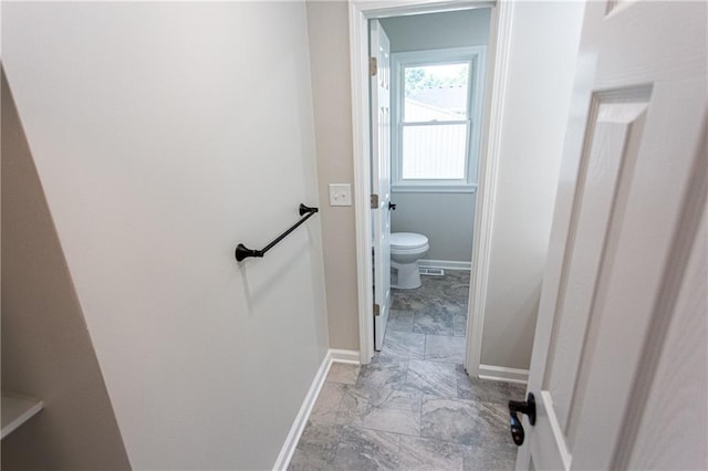 bathroom featuring marble finish floor, toilet, and baseboards