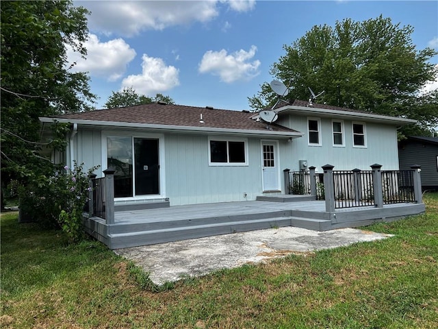 rear view of house with roof with shingles, a lawn, and a wooden deck