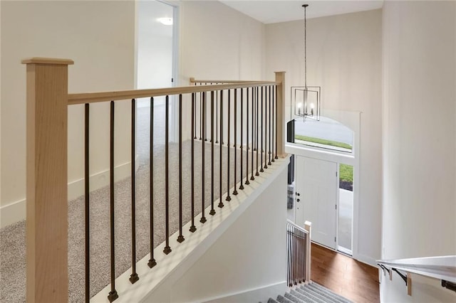 staircase with hardwood / wood-style flooring and a chandelier