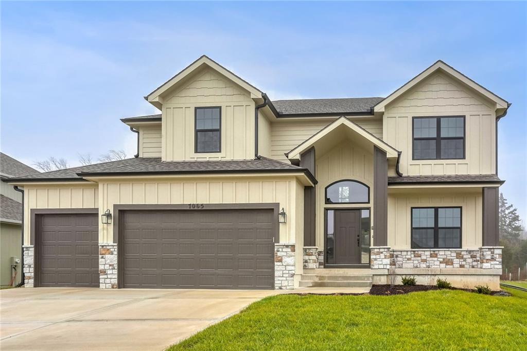 7065 NW Forest Lakes Dr, Parkville, MO 64152 - view of front of house featuring stone siding, a front lawn, board and batten siding, driveway, and a shingled roof