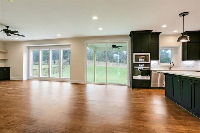 kitchen featuring hardwood / wood-style floors, tasteful backsplash, stainless steel dishwasher, and hanging light fixtures