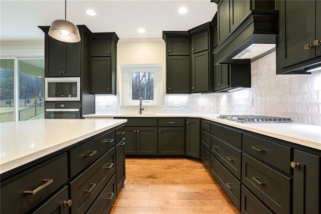 kitchen featuring built in microwave, sink, pendant lighting, light hardwood / wood-style floors, and black oven