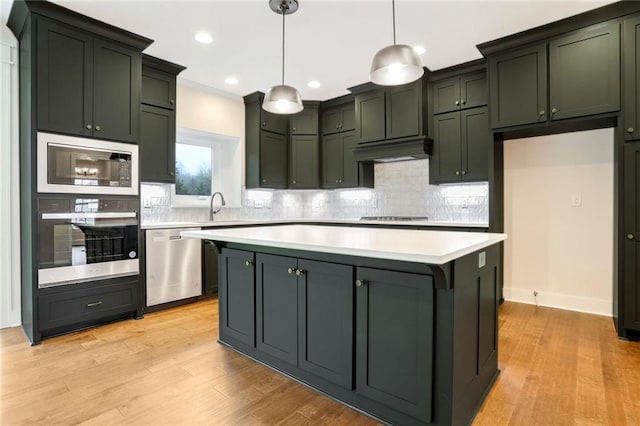 kitchen featuring a center island, hanging light fixtures, light hardwood / wood-style flooring, appliances with stainless steel finishes, and tasteful backsplash