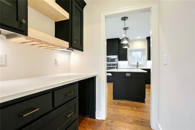 kitchen with a center island, oven, light hardwood / wood-style flooring, built in microwave, and decorative light fixtures