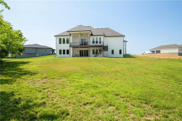 back of property featuring ceiling fan, a yard, and a balcony