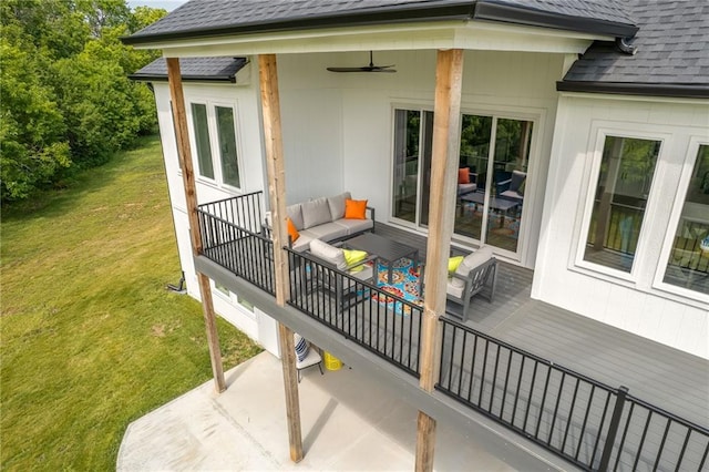 wooden deck with an outdoor living space, ceiling fan, and a lawn