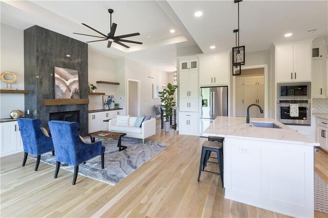 kitchen featuring light stone countertops, appliances with stainless steel finishes, sink, a center island with sink, and a fireplace