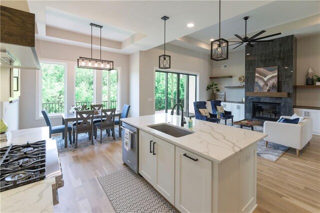 kitchen featuring white cabinets, an island with sink, a healthy amount of sunlight, and sink