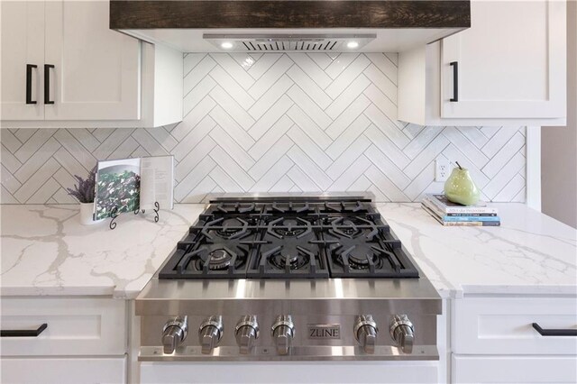 kitchen featuring decorative backsplash, white cabinetry, wall chimney exhaust hood, and light stone countertops