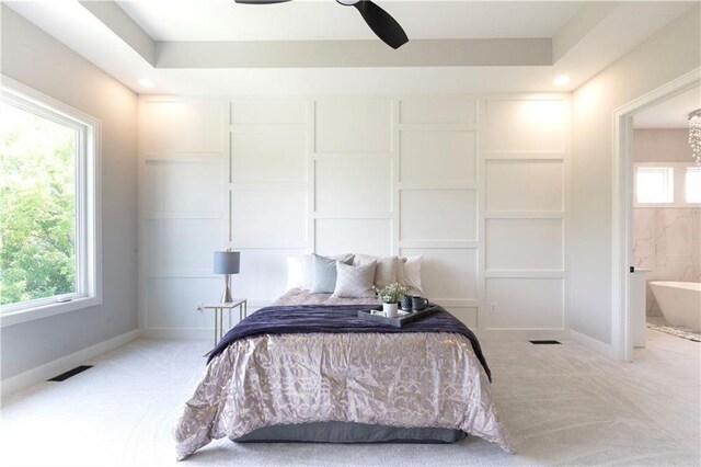 bedroom featuring ceiling fan, multiple windows, and ensuite bath