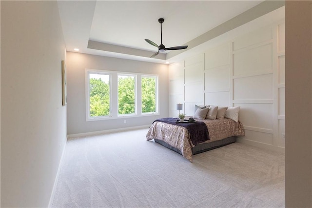 carpeted bedroom with a tray ceiling and ceiling fan