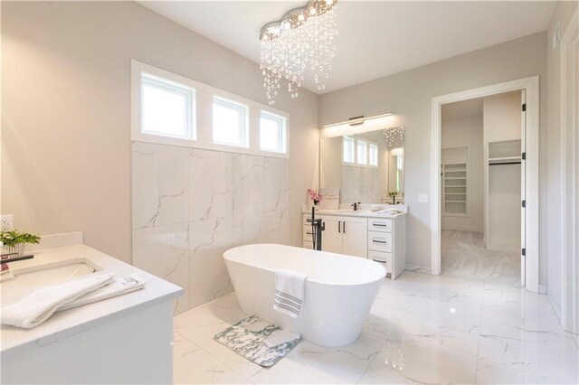 bathroom featuring a washtub, vanity, a chandelier, and tile walls