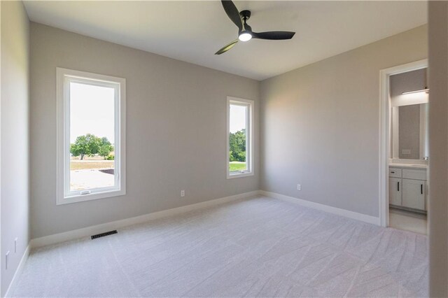 spare room with plenty of natural light, ceiling fan, and light colored carpet