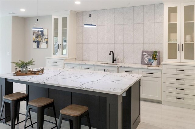 kitchen with white cabinets, pendant lighting, a kitchen breakfast bar, and sink