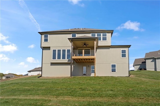 rear view of property with a yard, ceiling fan, and a balcony