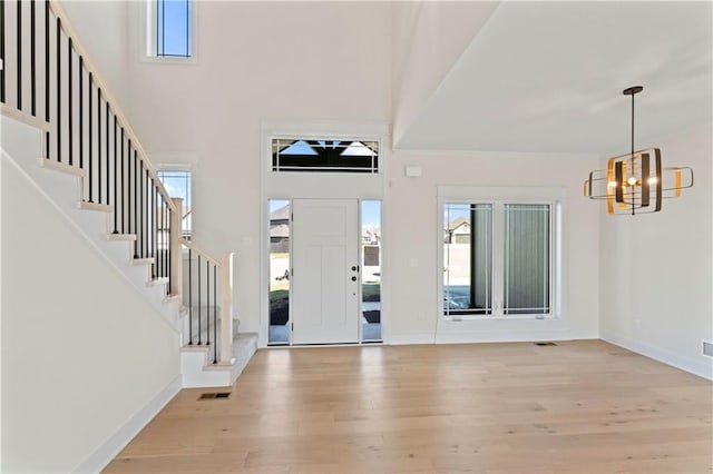 entrance foyer featuring light hardwood / wood-style floors, a notable chandelier, and a high ceiling