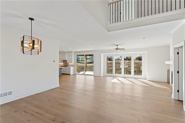 unfurnished living room with light hardwood / wood-style flooring and ceiling fan with notable chandelier