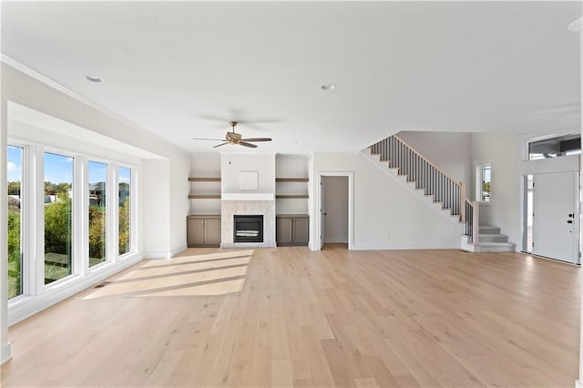 unfurnished living room featuring light hardwood / wood-style floors, a fireplace, and ceiling fan