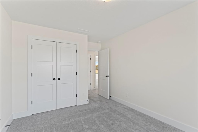 unfurnished bedroom with a closet and light carpet