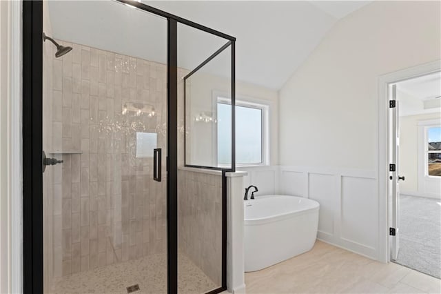 7075 NW Magnus Ct, Parkville, MO 64152 - bathroom with a stall shower, a freestanding tub, lofted ceiling, wainscoting, and a decorative wall