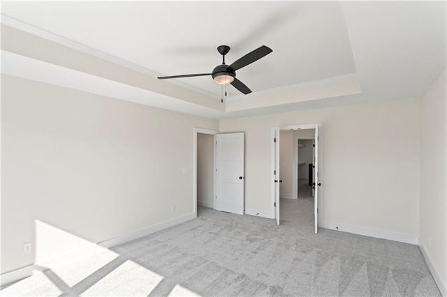 7075 NW Magnus Ct, Parkville, MO 64152 - unfurnished bedroom with baseboards, light colored carpet, a raised ceiling, and ceiling fan