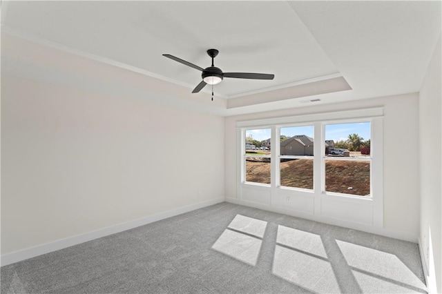 carpeted empty room with crown molding, ceiling fan, and a raised ceiling