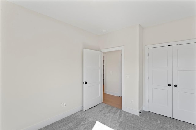 unfurnished bedroom with a closet and light carpet