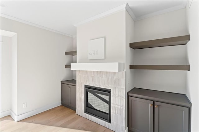 7075 NW Magnus Ct, Parkville, MO 64152 - unfurnished living room featuring ornamental molding, light wood finished floors, baseboards, and a tiled fireplace
