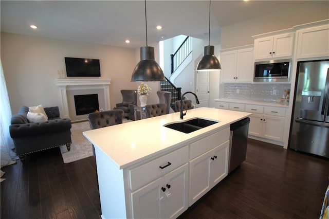 kitchen featuring decorative light fixtures, an island with sink, white cabinetry, sink, and stainless steel appliances