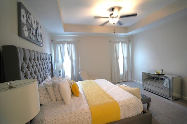 bedroom with a tray ceiling, light colored carpet, and ceiling fan