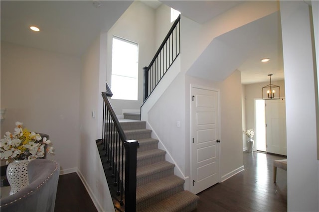 stairs with hardwood / wood-style floors and an inviting chandelier