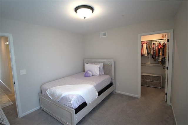 carpeted bedroom with a walk in closet and a closet