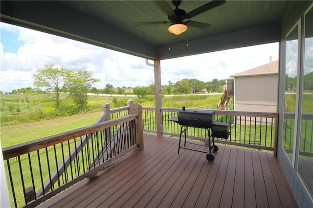 wooden deck with a rural view, a lawn, and ceiling fan