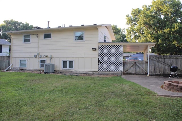 rear view of property featuring a fire pit, a patio, central air condition unit, and a lawn