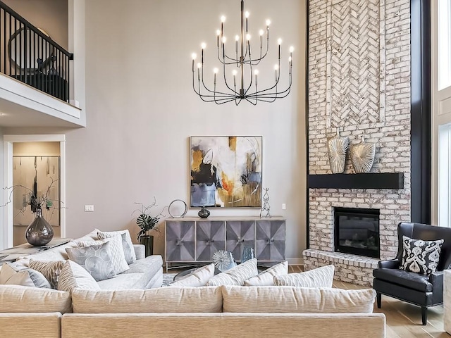 living room featuring hardwood / wood-style floors, a brick fireplace, a notable chandelier, and a high ceiling