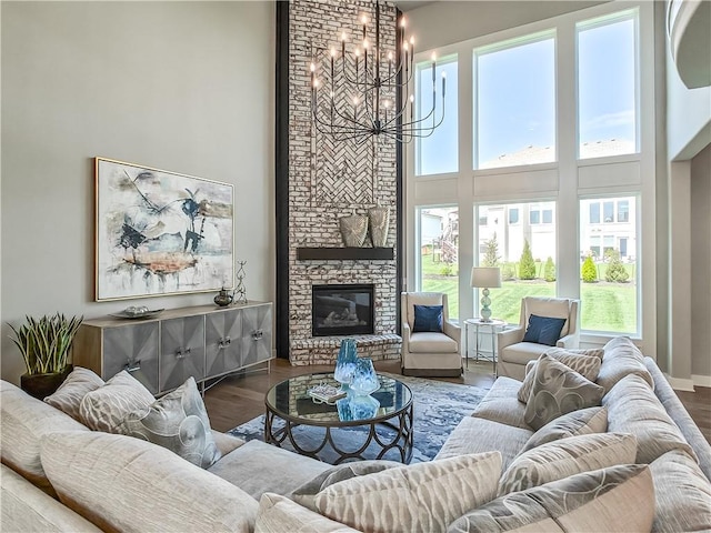 17212 Nieman Rd, Overland Park, KS 66221 - living room featuring a towering ceiling, a chandelier, healthy amount of natural light, a brick fireplace, and wood finished floors