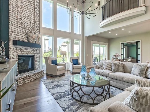 17212 Nieman Rd, Overland Park, KS 66221 - living room featuring wood finished floors, a towering ceiling, a brick fireplace, a chandelier, and recessed lighting