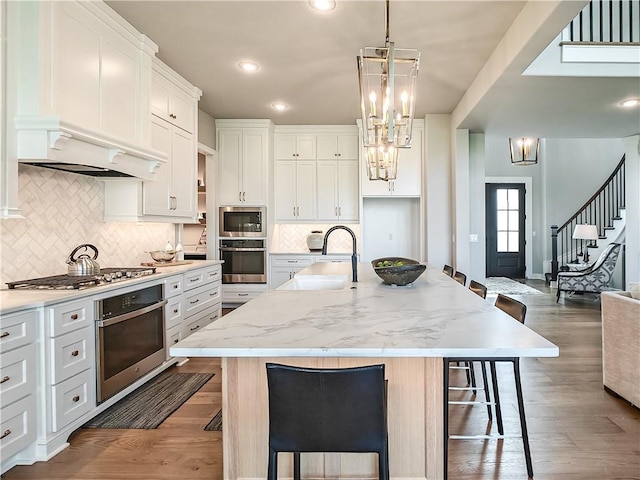 17212 Nieman Rd, Overland Park, KS 66221 - kitchen with stainless steel appliances, a sink, a breakfast bar area, white cabinetry, and a center island with sink