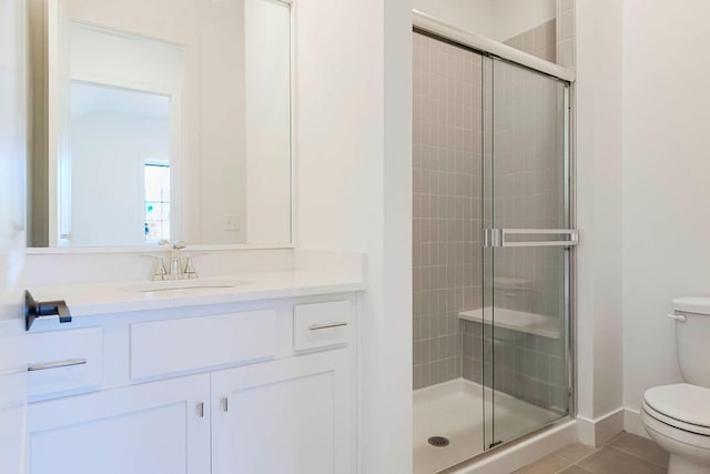 bathroom featuring tile patterned flooring, vanity, a shower with shower door, and toilet