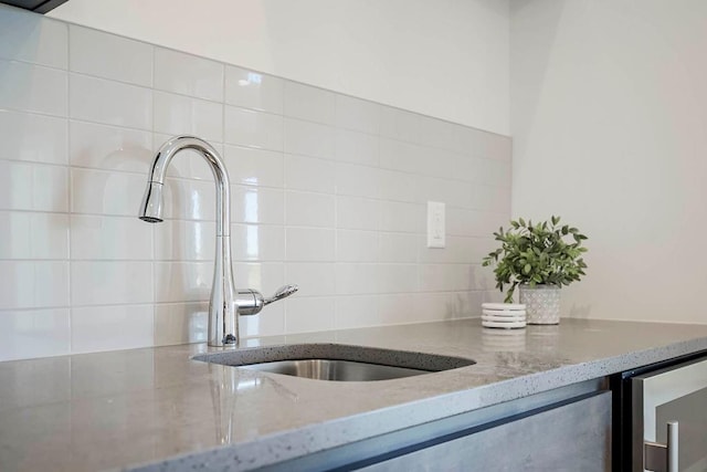 room details with beverage cooler, light stone countertops, and sink